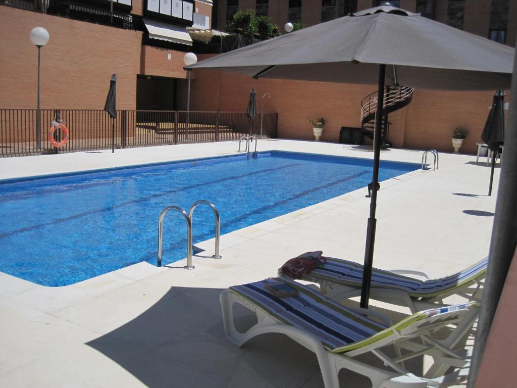 una silla y una sombrilla junto a la piscina en Apartamento Las Rozas Village en Las Rozas de Madrid