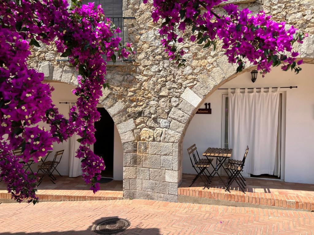 un arco con flores púrpuras frente a un edificio en Apartamento La Palmera Plaza, en Sant Martí d’Empúries
