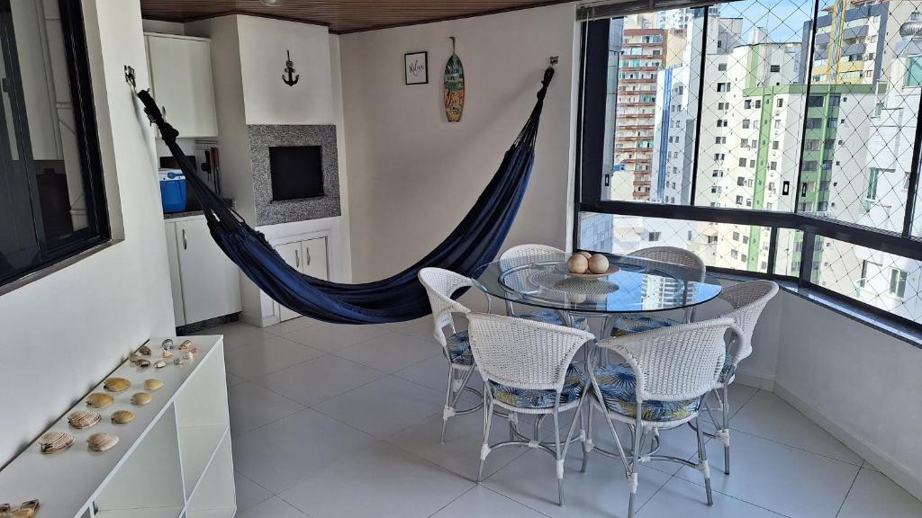 comedor con mesa de cristal y sillas en Apartamento na Praia Central de BC, ideal para você e sua família, en Balneário Camboriú