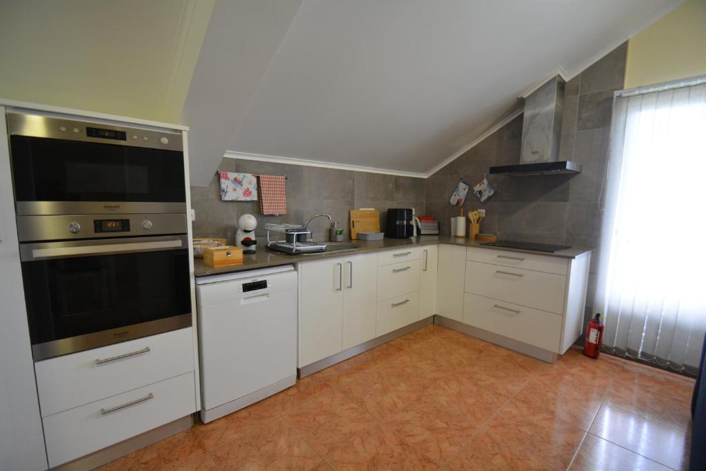 uma cozinha com armários brancos e electrodomésticos de aço inoxidável em Casinha das Hortênsias em Horta