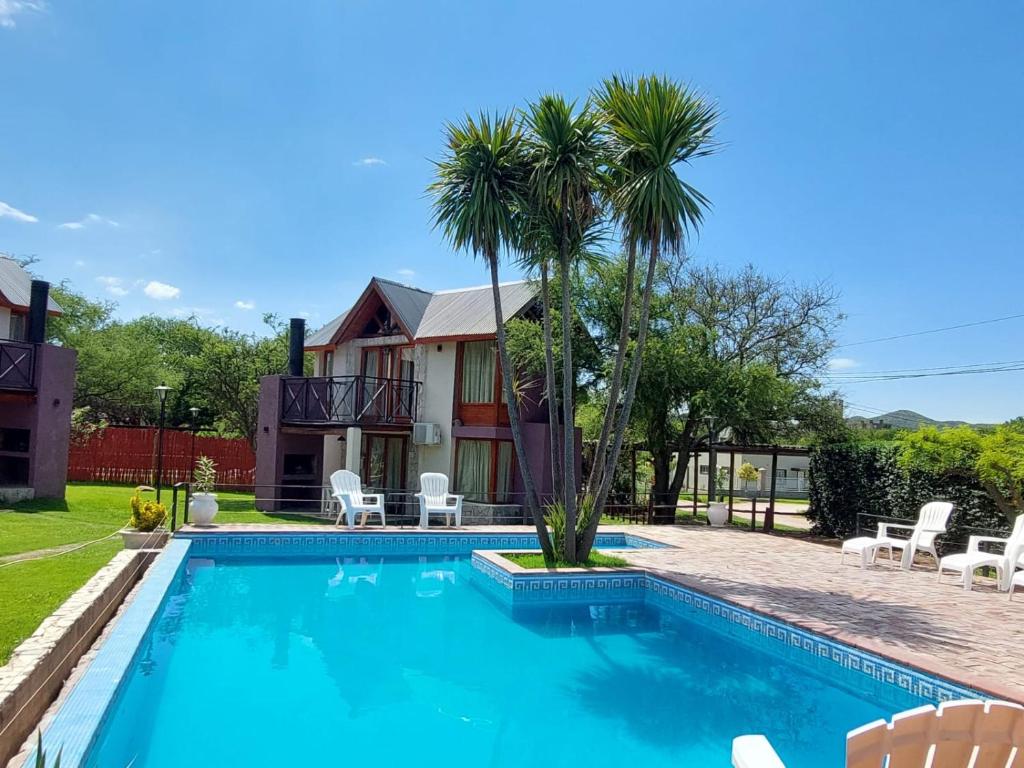 a swimming pool in front of a house with a palm tree at Cabañas Ayres del Lago 2 in Potrero de los Funes