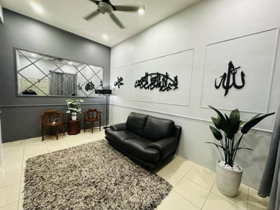 ein Wohnzimmer mit einem schwarzen Ledersessel und einem Teppich in der Unterkunft FATEHA HOMESTAY PENDANG in Pendang