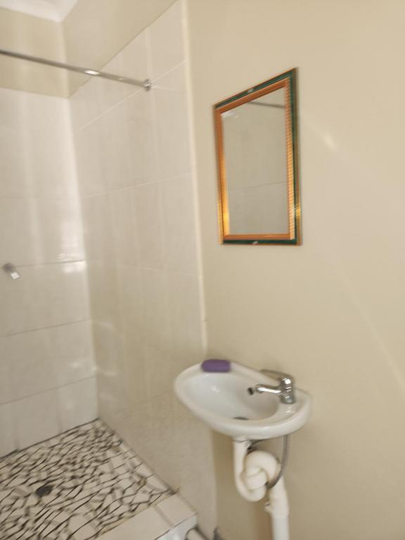een witte badkamer met een wastafel en een spiegel bij HUNTERS NEST GUEST HOUSE MAFIKENG in Mahikeng
