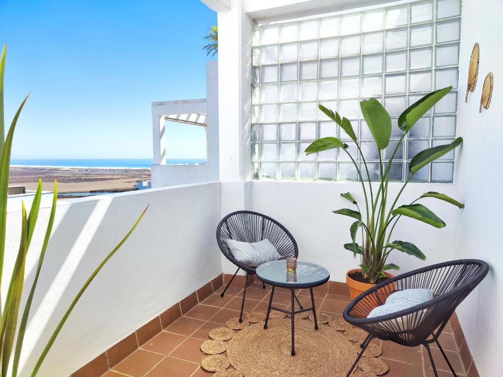 duas cadeiras e uma mesa numa varanda com uma planta em Ático con fantásticas vistas em Conil de la Frontera