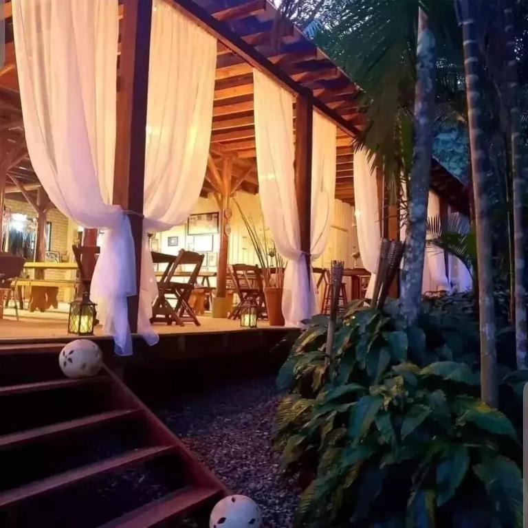 Habitación con cortinas blancas, escaleras y mesas. en Sitio do Sol quarto wc compartilhado, en Guabiruba