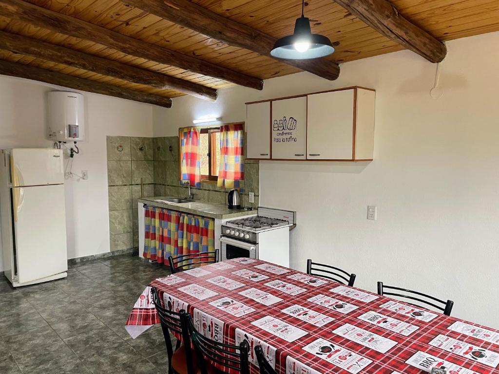 a kitchen with a table and a refrigerator at Cabañas Llitulun in Alpa Corral