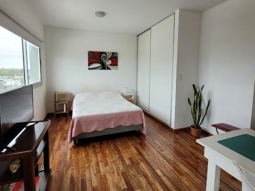 ein Schlafzimmer mit einem Bett in einem Zimmer mit Holzböden in der Unterkunft Luminoso Monoambiente in La Plata