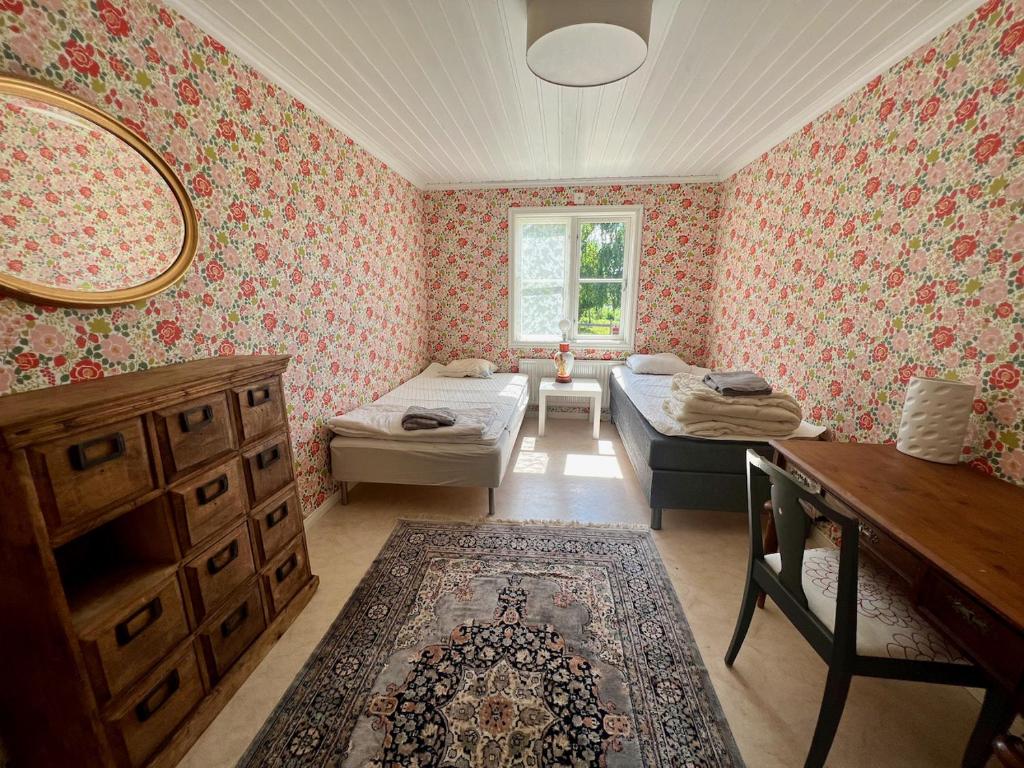 1 dormitorio con 2 camas, tocador y espejo en Idylliskt hus med sjöutsikt., en Östhammar