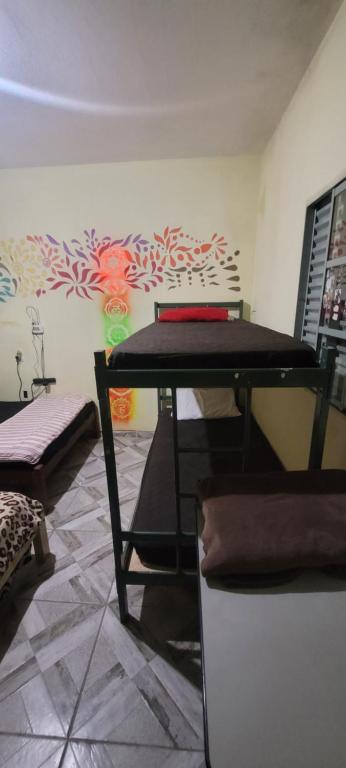 a room with a table and a wall with flowers at Casa da Luz stl Hostel in São Thomé das Letras
