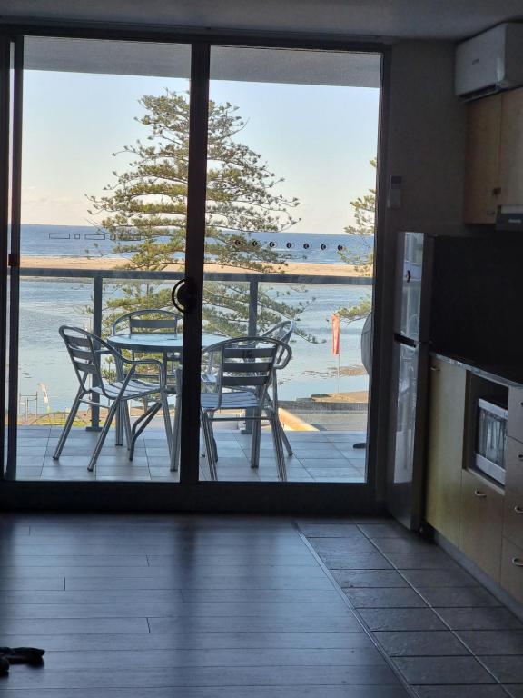 a kitchen with a view of a table and chairs at The Entrance Superb Apartment The Entrance NSW with Ocean - Lake Views in The Entrance
