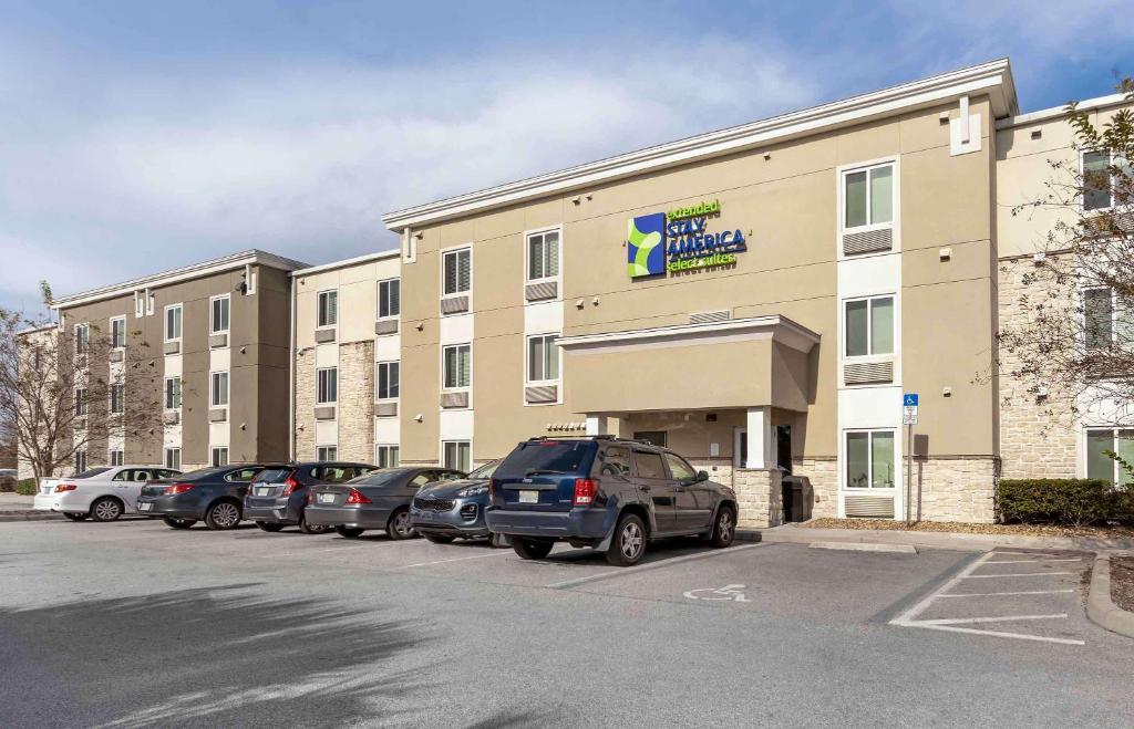 a large building with cars parked in front of it at Extended Stay America Select Suites - Orlando - Airport in Orlando