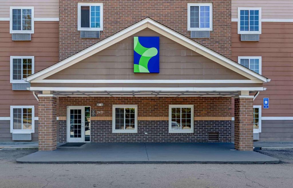 a red brick building with a blue and green sign on it at Extended Stay America Select Suites - Atlanta - Chamblee in Atlanta