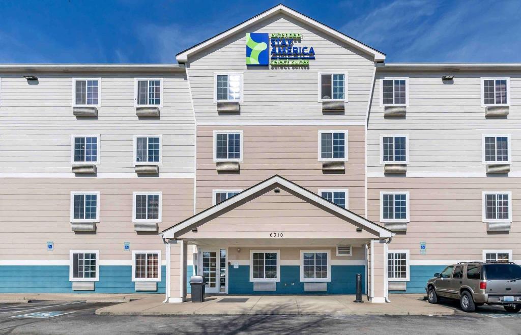 a large white and blue building with a parking lot at Extended Stay America Select Suites - Louisville - South 