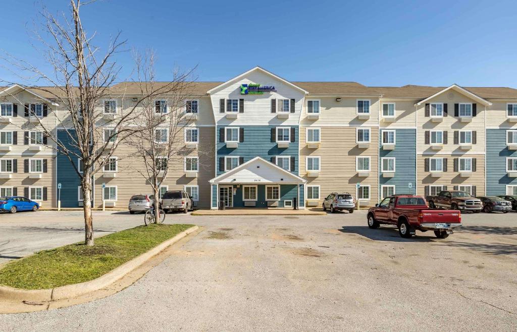 a large building with a red truck parked in front of it at Extended Stay America Select Suites - Fayetteville - I-49 in Fayetteville