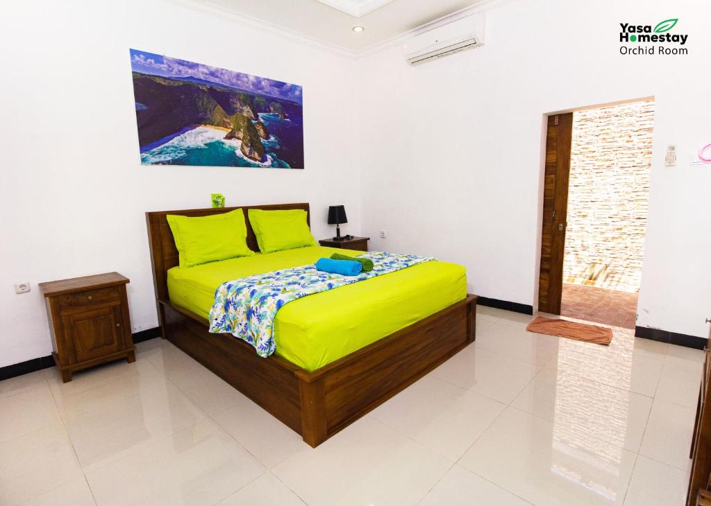 a bedroom with a bed and a painting on the wall at Yasa Homestay in Nusa Penida