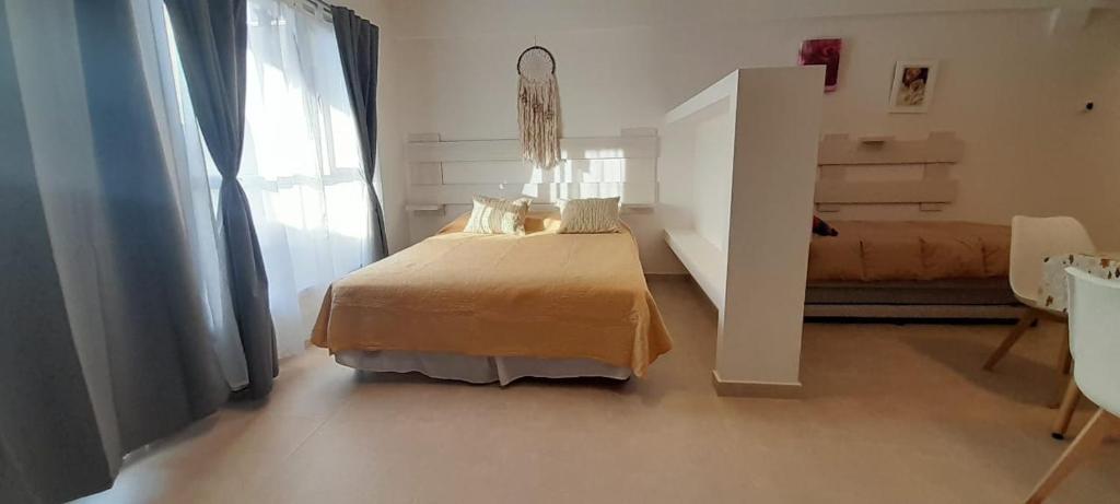 a white bedroom with a bed and a window at Amplio Estudio de lujo con balcon y parrilla in Puerto Madryn