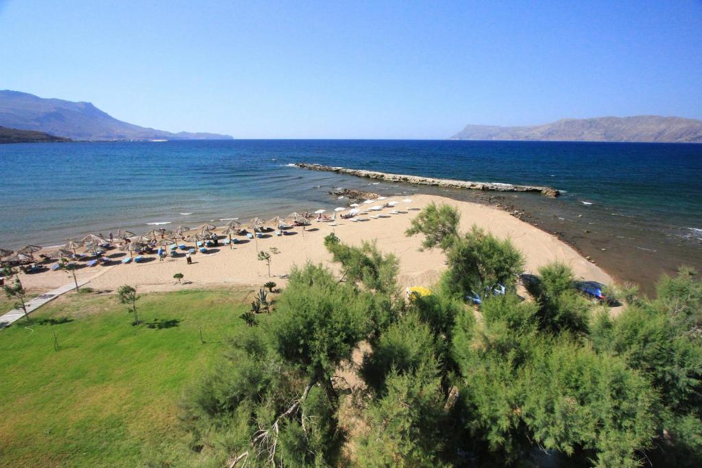 a beach with a bunch of umbrellas and the ocean at Nautilus Bay Hotel in Kissamos