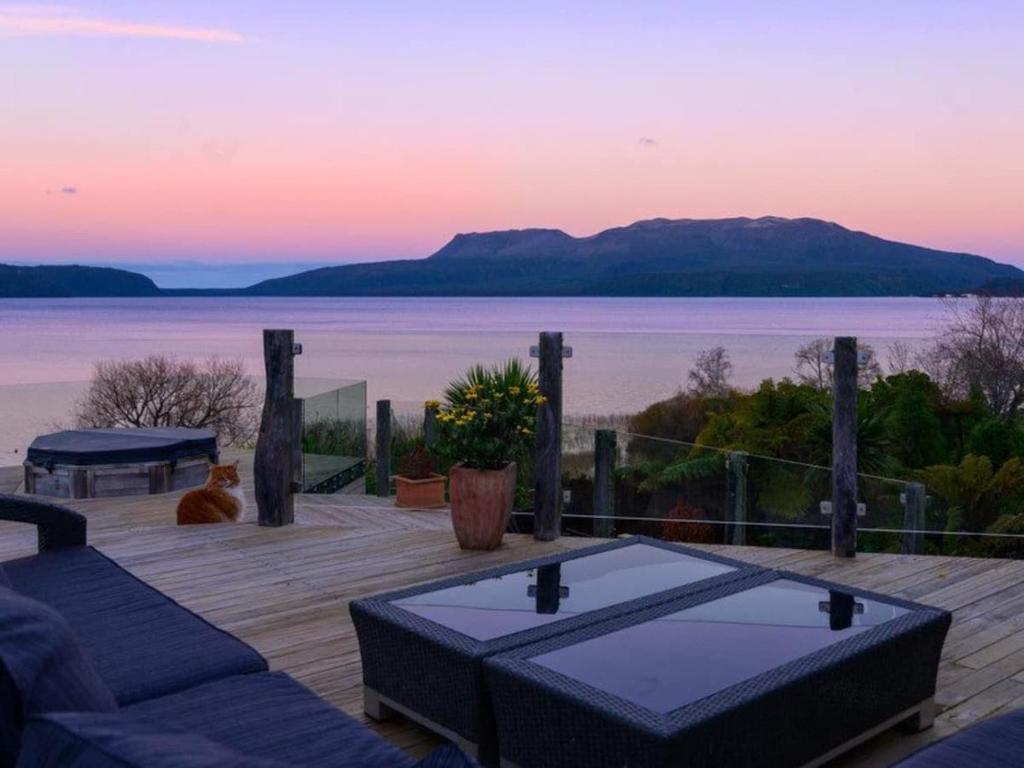 a deck with a view of the water and a table at The Terrace Lake Tarawera in Lake Tarawera