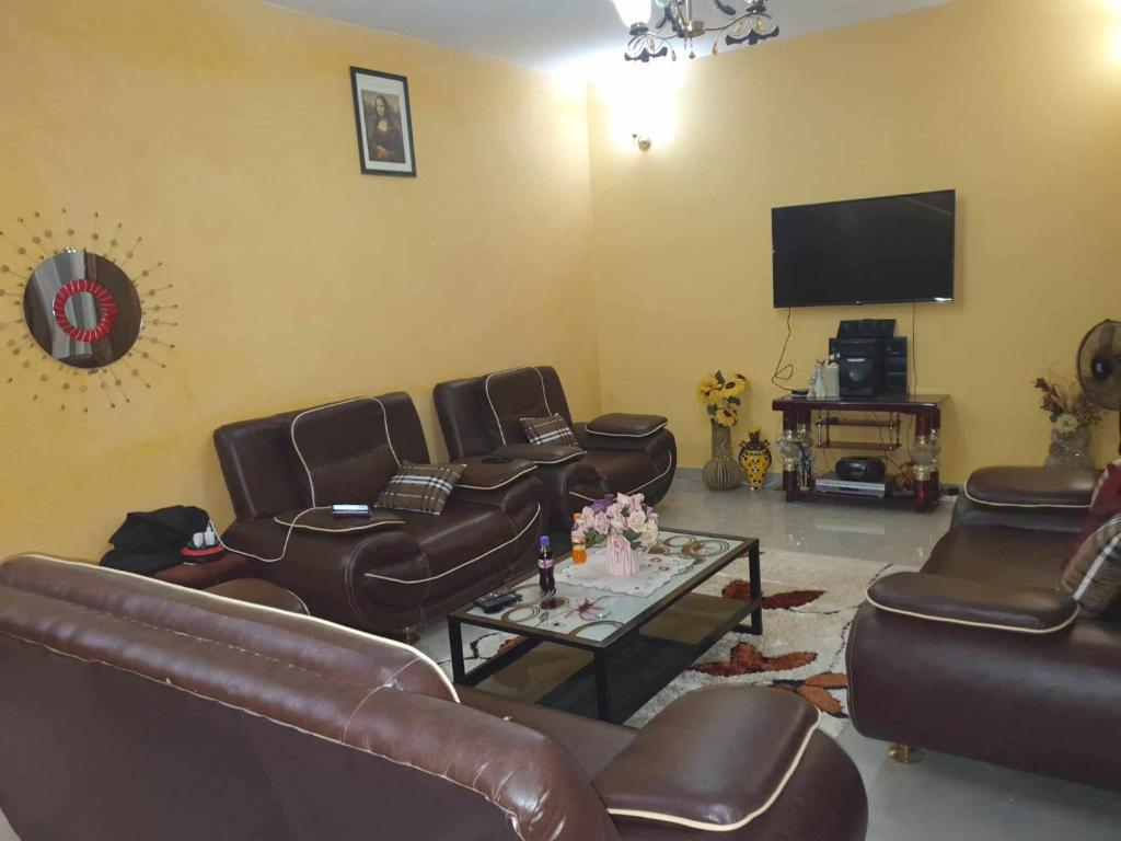 sala de estar con muebles de cuero y TV de pantalla plana en SALY KEUR EMMA, en Malikounda Sas