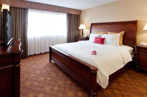 a hotel room with a large bed with red pillows at Wyndham Southbury in Southbury