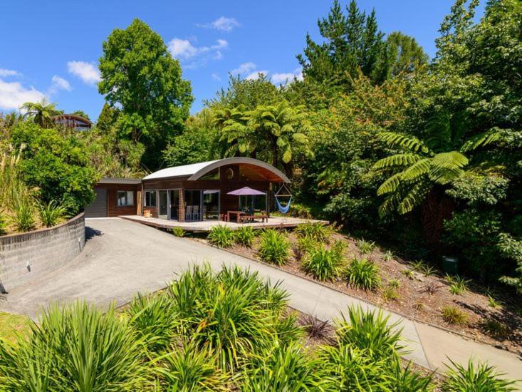a house with a pavilion in the middle of a garden at FlaxWater Lake Tarawera in Lake Tarawera