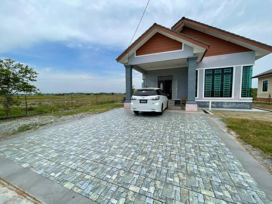 a car parked in front of a small house at Nice bungalow with view of paddy fields in Tumpat