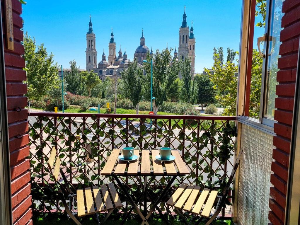 a table on a balcony with a view of a city at Front Views To El Pilar ComoTuCasa in Zaragoza