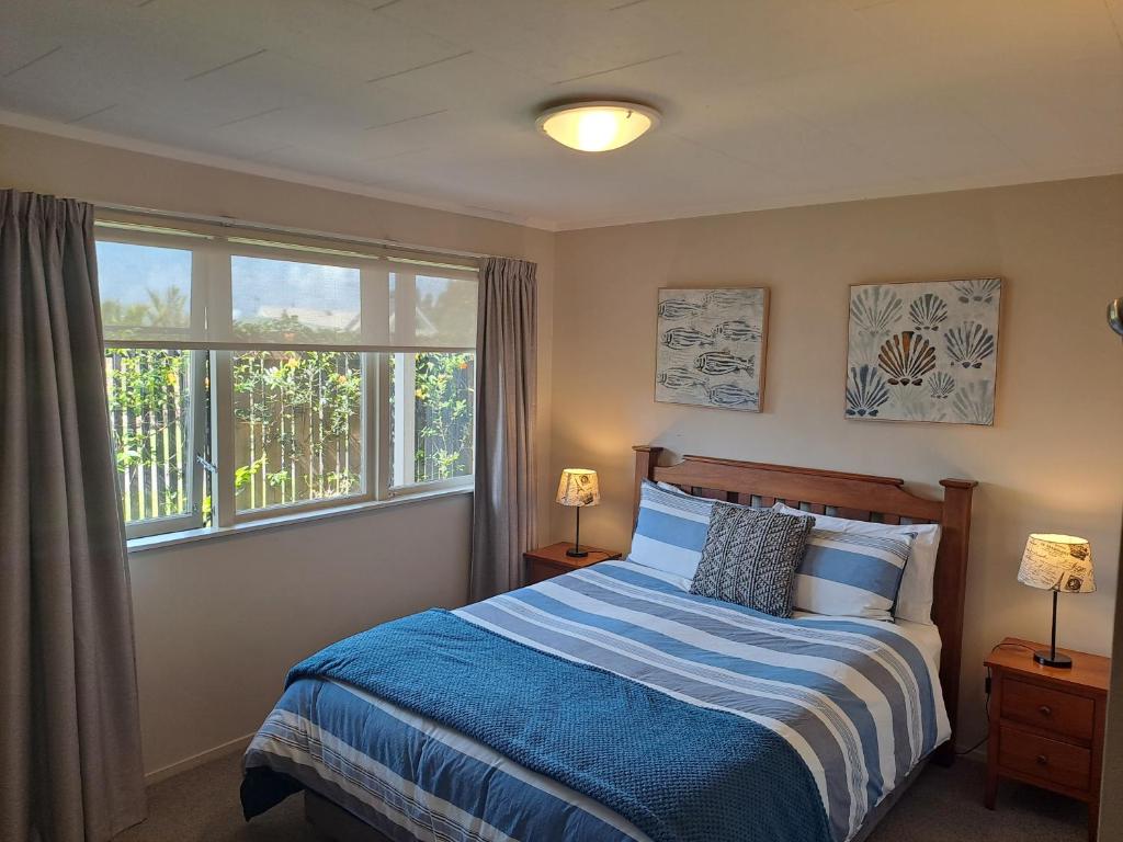 een slaapkamer met een bed en een groot raam bij Feel at Home in Tauranga