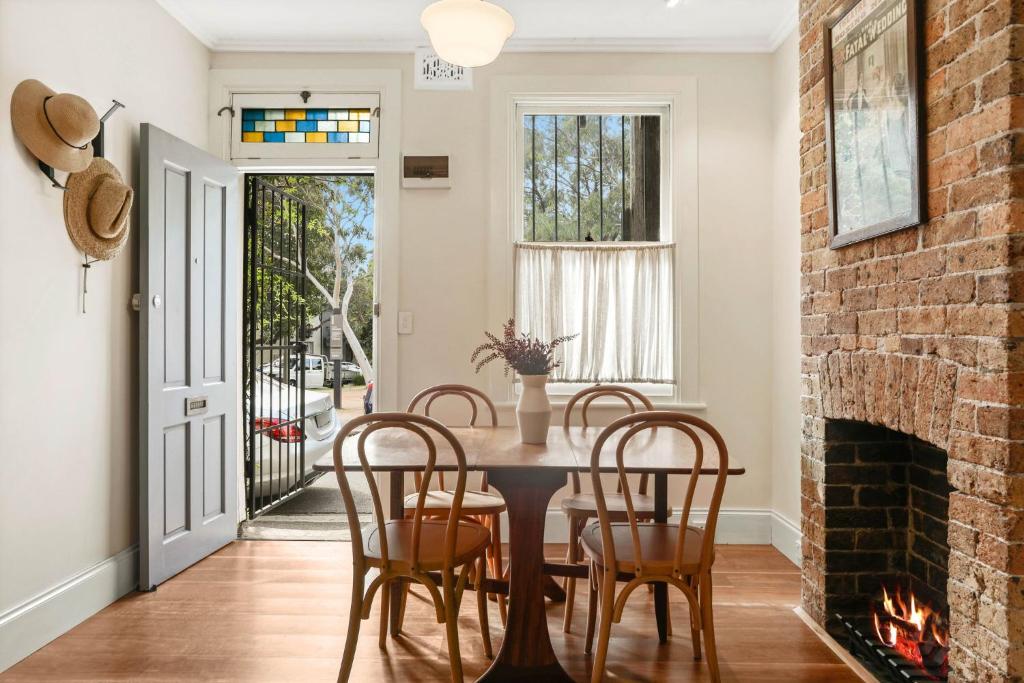 - une salle à manger avec une cheminée en briques, une table et des chaises dans l'établissement Redfern Terrace House l 2 Bedrooms & Loft, à Sydney