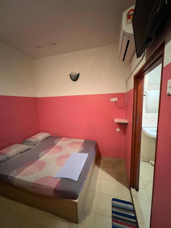 ein Schlafzimmer mit einem Bett und einer roten Wand in der Unterkunft TGT MOTEL Gurun in Kampung Gurun