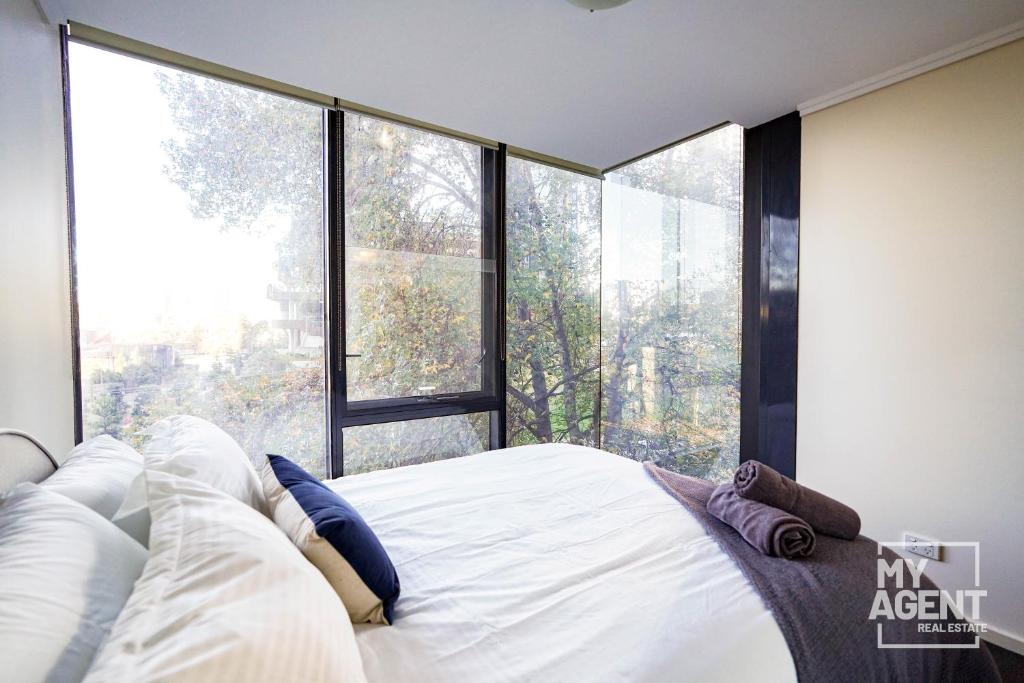 een slaapkamer met een bed en een groot raam bij Spacious Apartment in Southbank - Sleeps 6 in Melbourne