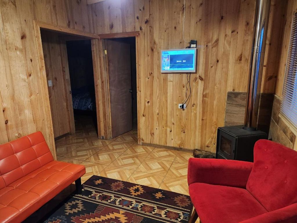 ein Wohnzimmer mit einem Sofa und einem Herd in der Unterkunft Cabaña 2 Entre Copihues in Osorno