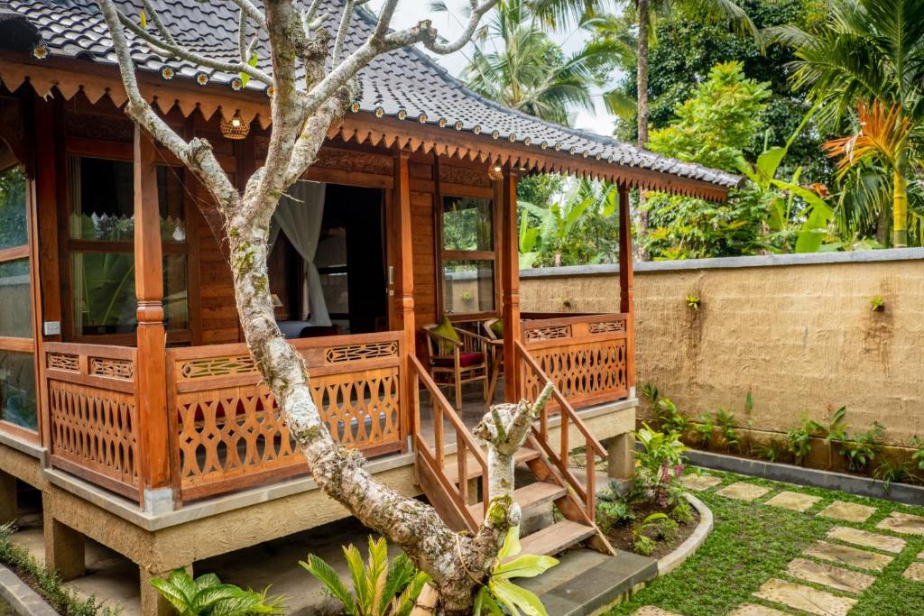 ein Holzhaus mit einem Baum davor in der Unterkunft Toya Sutra Villa in Tampaksiring