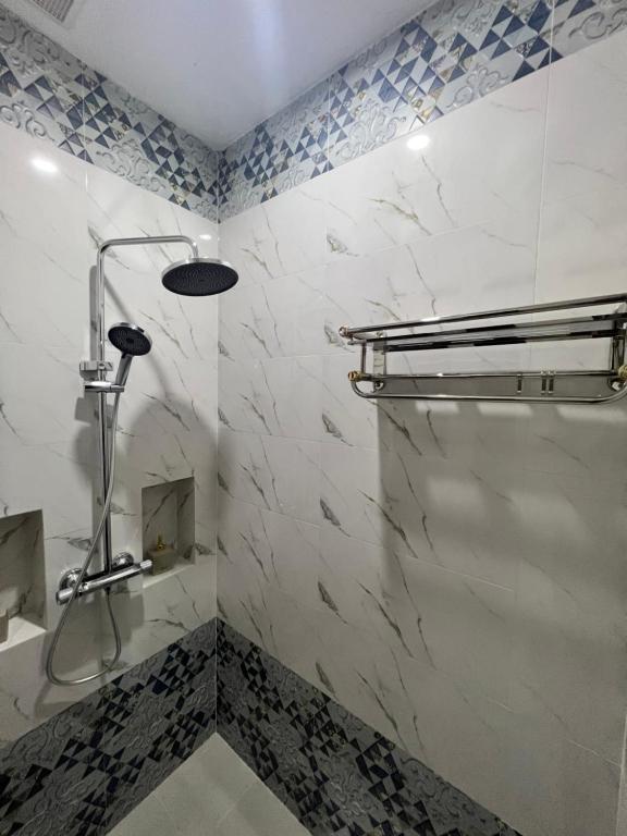 La salle de bains est pourvue d'une douche et de murs en marbre blanc. dans l'établissement NamKhan Riverside, à Luang Prabang
