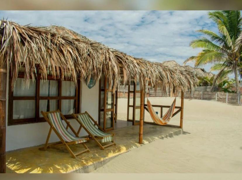 two chairs under a straw hut on the beach at Varadero Bungalows in Los Órganos