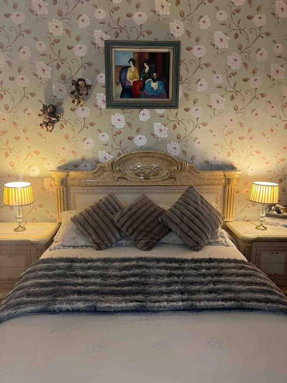 a bedroom with a large bed with flowers on the wall at Nice comfy house in London