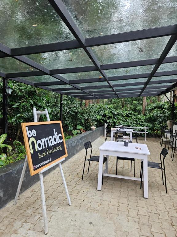 a sign that says be nomada with tables and chairs at beNomadic Eco Hostel, Madikeri, Coorg in Suntikoppa