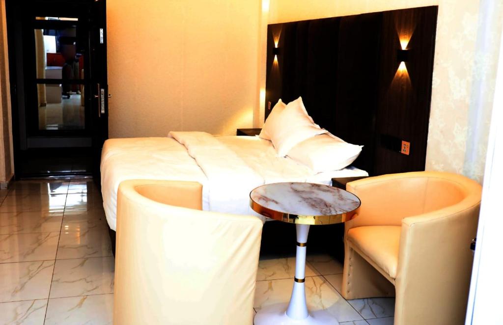 ein Hotelzimmer mit einem Bett, einem Tisch und einem Stuhl in der Unterkunft Texas Royal Hotel in Pokuase