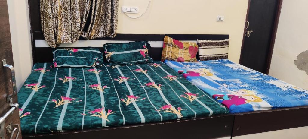 ein Bett mit einer Bettdecke und Kissen darauf in der Unterkunft Brijlok Dham homestay in Mathura