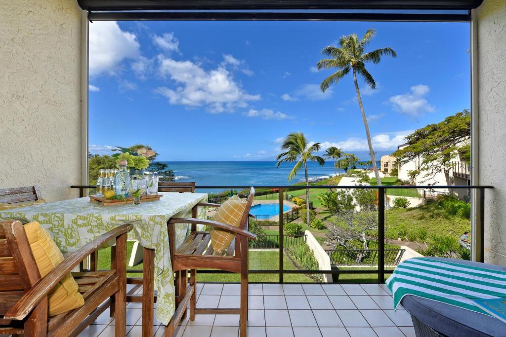 a balcony with a table and chairs and a view of the ocean at Napili Point C40 in Kahana