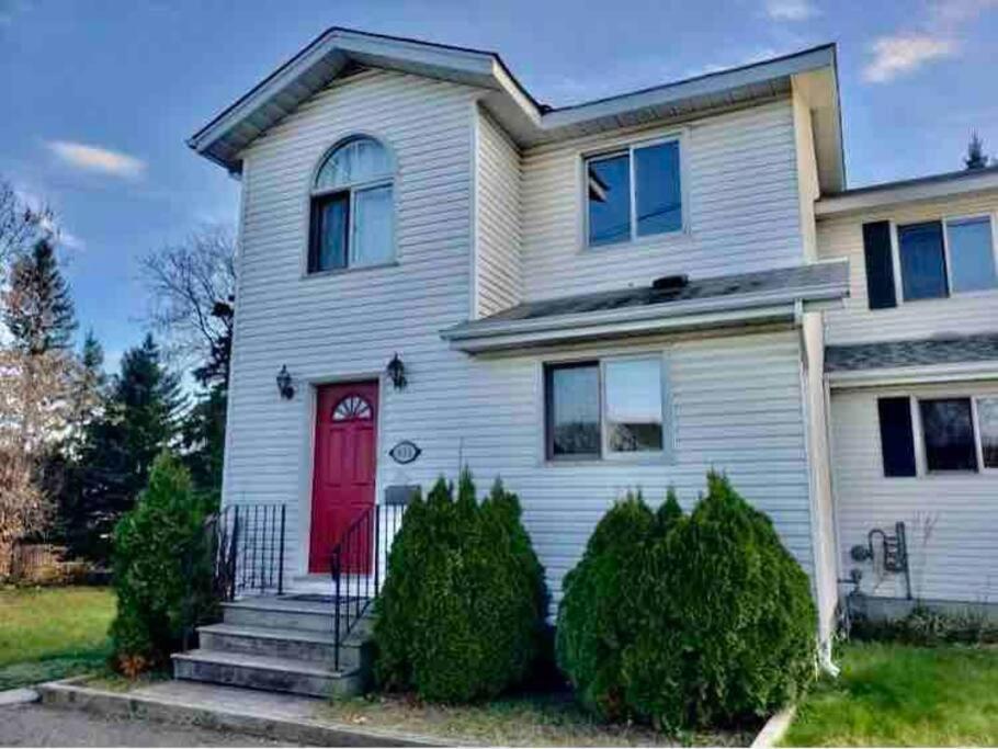 a white house with a red door at Furnished Townhouse w parking by Hospital & University! in Thunder Bay