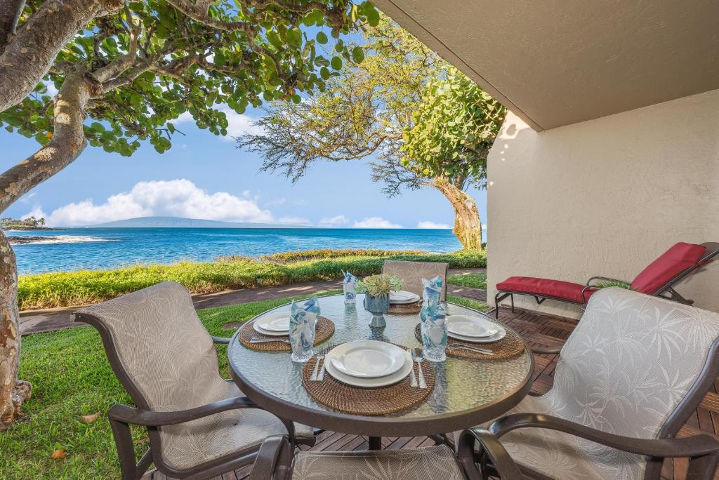 een tafel en stoelen op een patio met uitzicht op de oceaan bij Napili Point A9 in Kahana