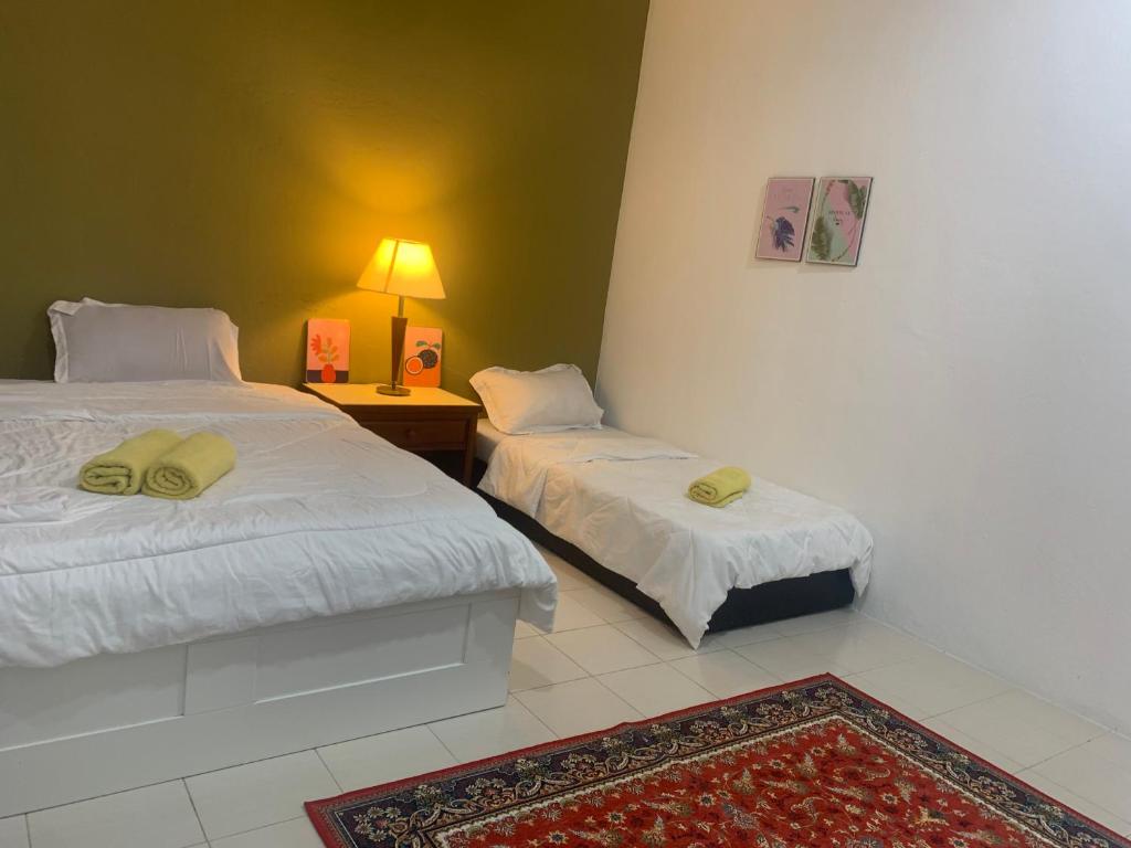 1 dormitorio con 2 camas y mesa con lámpara en Rerama Room Stay Langkawi, en Pantai Cenang