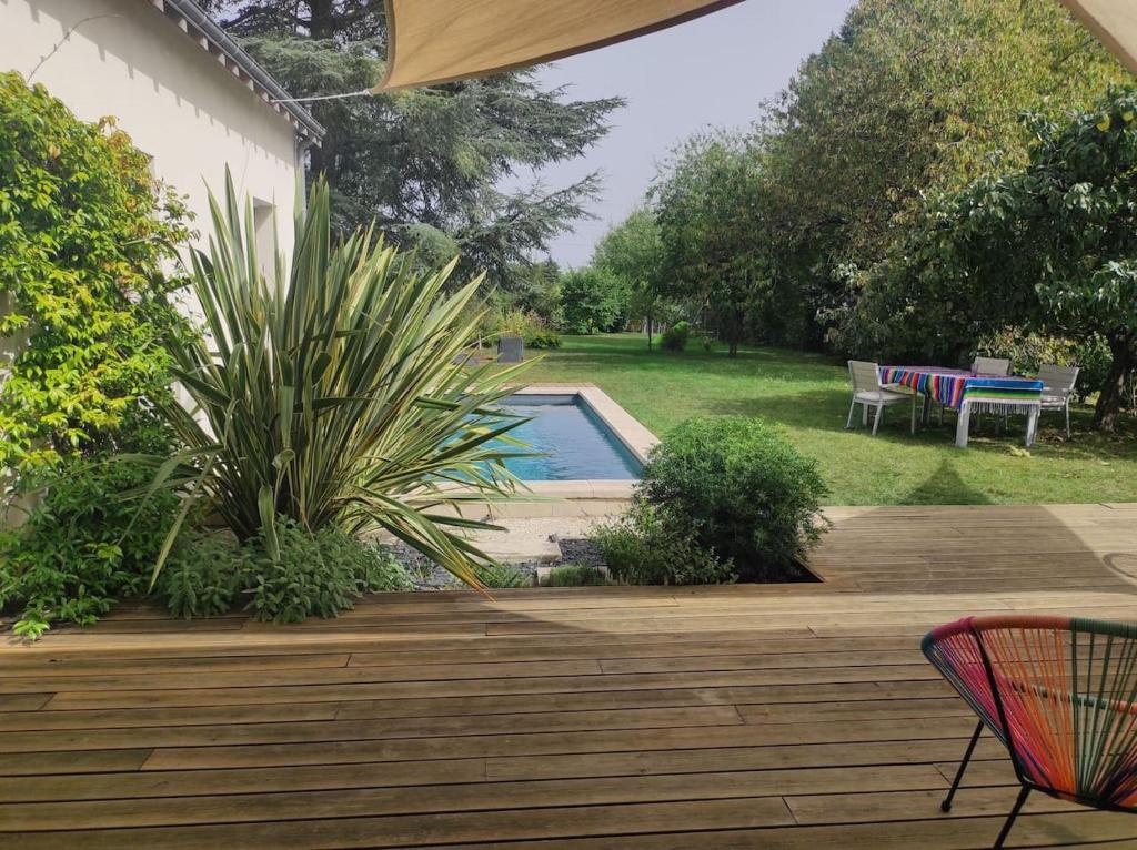 un patio trasero con piscina y terraza de madera en Le havre du grand cèdre, en Fondettes