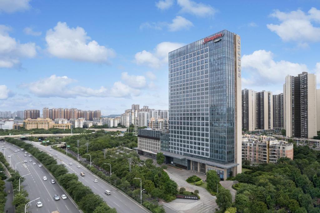 a tall glass building in a city with a highway at Hampton by Hilton Nanning Jiangnan in Nanning