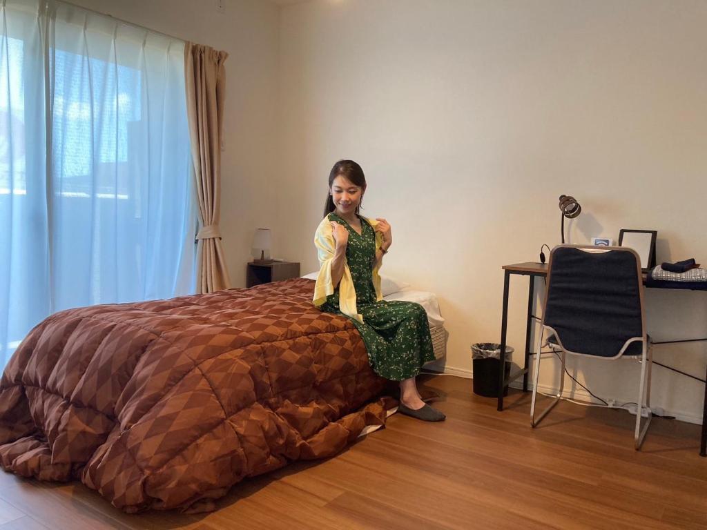 a young girl sitting on top of a bed at 笠岡　潮待ちHOTEL 
