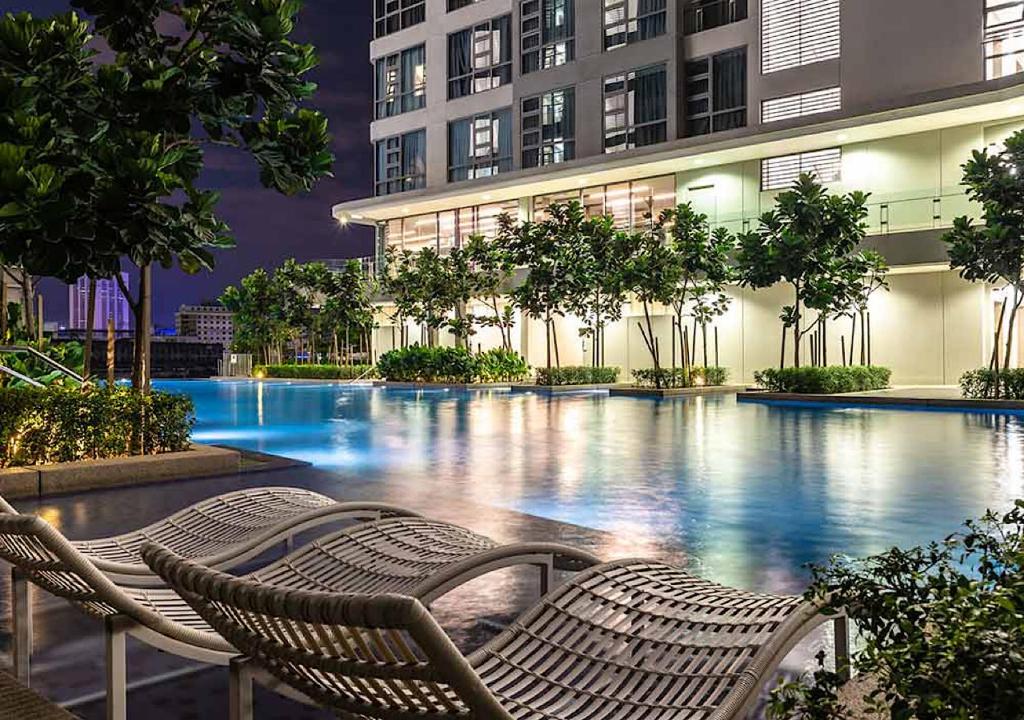 a swimming pool with two chairs in front of a building at Robertson PanoramaKL Suites in Kuala Lumpur