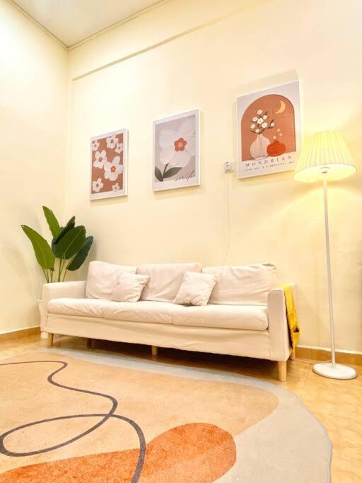 a living room with a white couch and a lamp at 暖居Mersing Muji Cottage 0.3km Jeti Mersing Centre in Mersing
