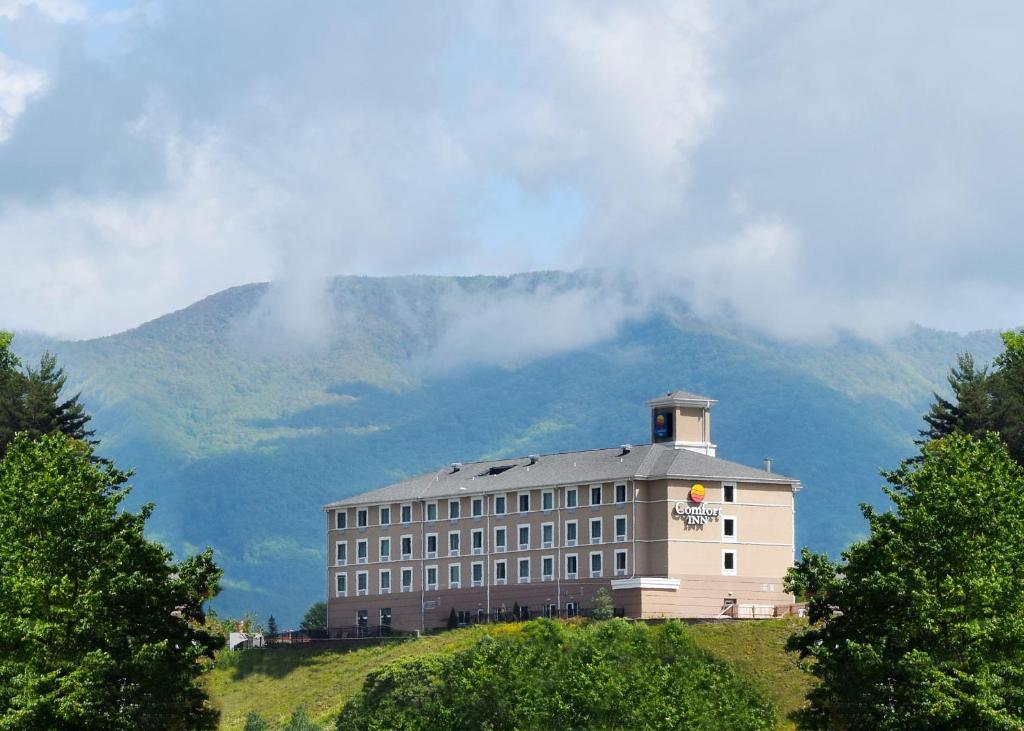 a building on a hill with a mountain in the background at Comfort Inn Sylva - Cullowhee in Dillsboro