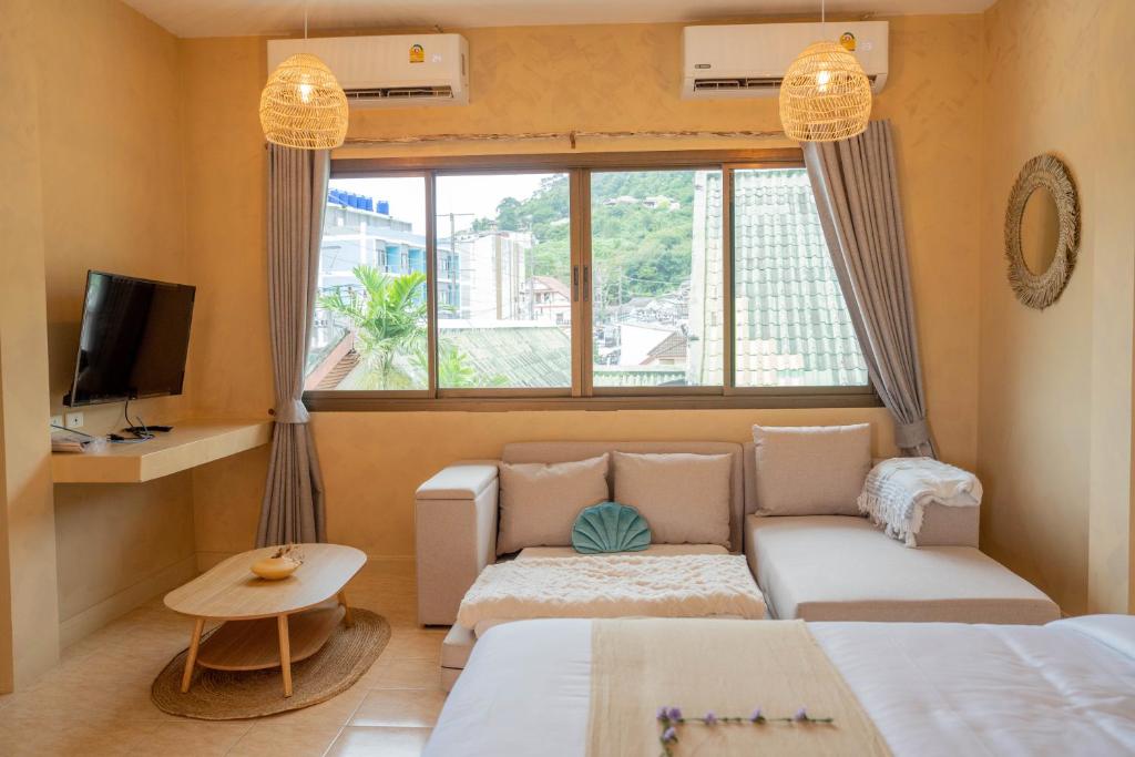 a room with two beds and a couch and a tv at Rustic and Blue Getaway in Patong Beach